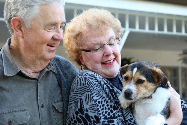 An upbeat joyful elderly man and woman couple in love at home with dog